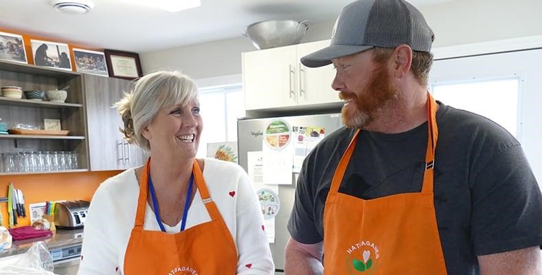 two people in aprons, smiling