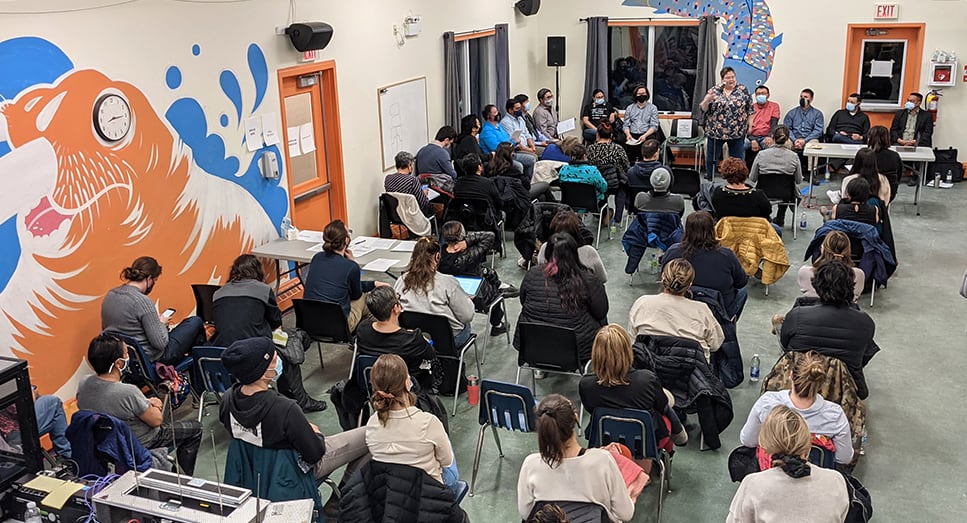 a group of people are listening to a speaker at the front of the room